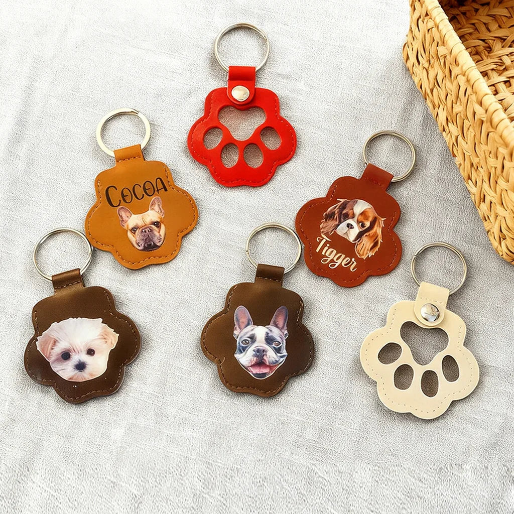 Back view of a custom paw-shaped leather pet fur keepsake keychain showing a high-definition color portrait of a dog and the engraved name.