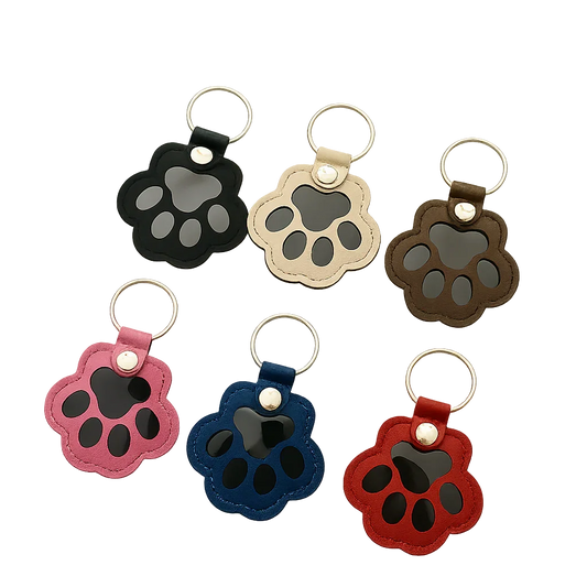 Custom paw-shaped leather pet fur keepsake keychain in black, beige, and brown, featuring a transparent window for fur storage and a personalized portrait on the back.