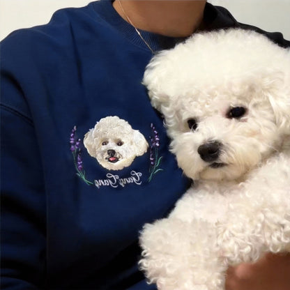 Model wearing a navy blue custom pet portrait sweatshirt while holding a white Bichon Frise dog