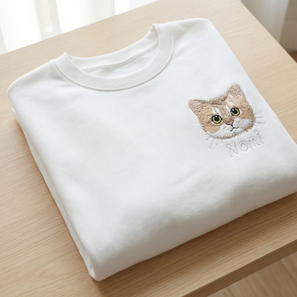 Folded white custom embroidered pet sweatshirt showing a detailed cat portrait and name - premium pet lover gift