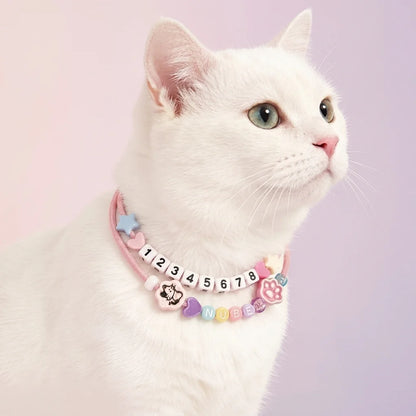 Elegant white cat wearing a personalized pink-themed bead necklace with its name, demonstrating pet jewelry for cats.